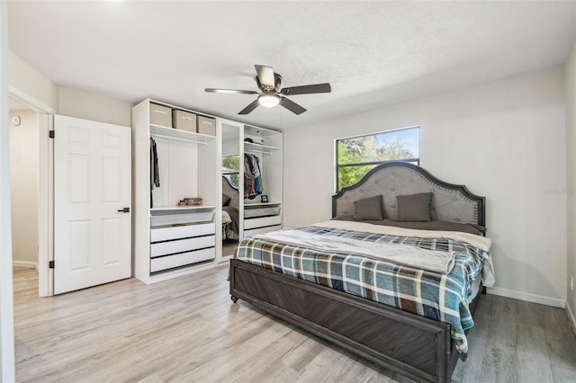 bedroom with ceiling fan, a closet, a textured ceiling, and light hardwood / wood-style flooring