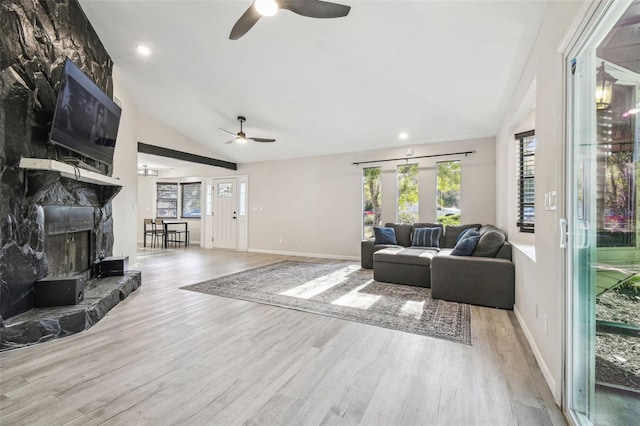 living room with a fireplace, light wood-type flooring, ceiling fan, and lofted ceiling