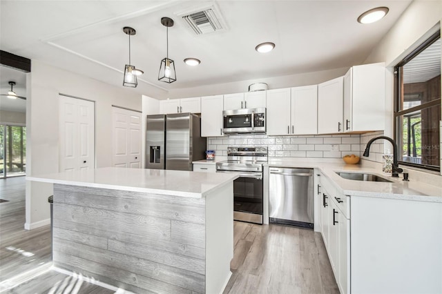 kitchen featuring pendant lighting, a center island, a healthy amount of sunlight, and appliances with stainless steel finishes