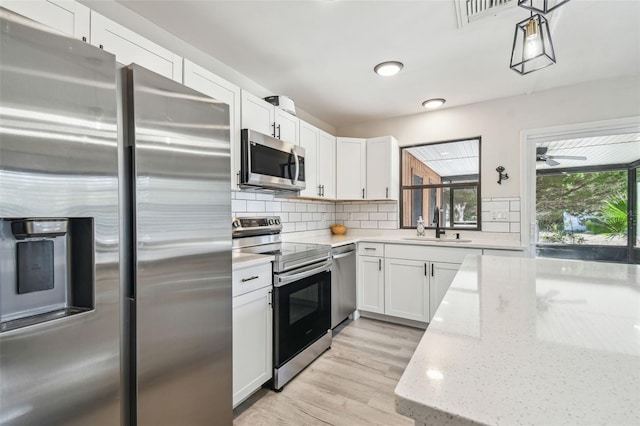 kitchen featuring white cabinets, sink, light wood-type flooring, light stone countertops, and stainless steel appliances