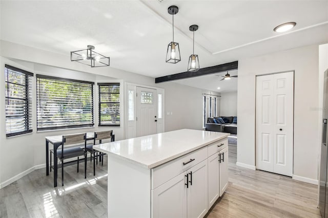 kitchen with ceiling fan, pendant lighting, light hardwood / wood-style flooring, white cabinets, and a kitchen island