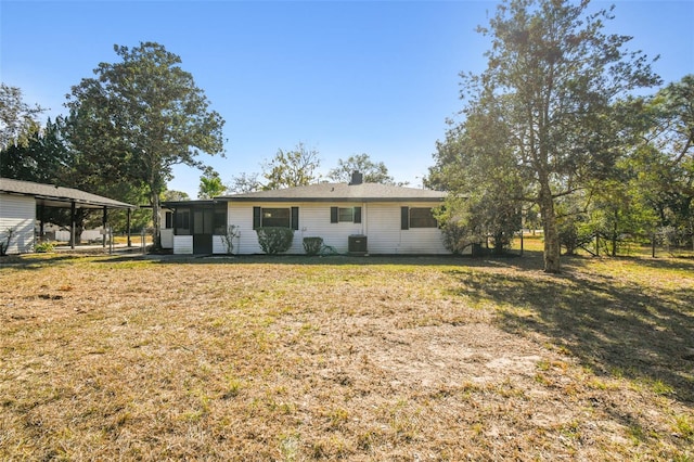 view of front of house with a sunroom, cooling unit, a carport, and a front lawn