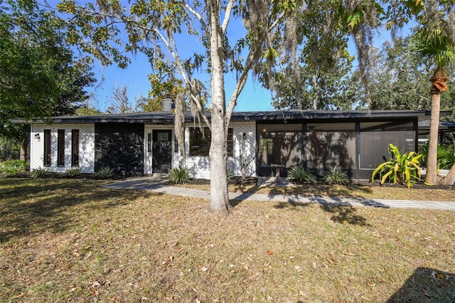 ranch-style house with a sunroom and a front lawn