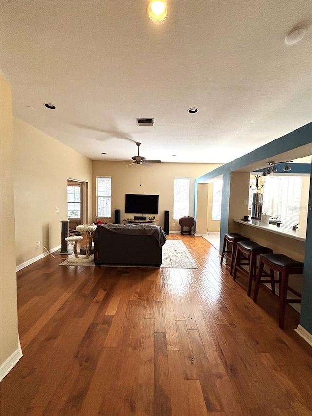 living room featuring hardwood / wood-style flooring, plenty of natural light, ceiling fan, and a textured ceiling