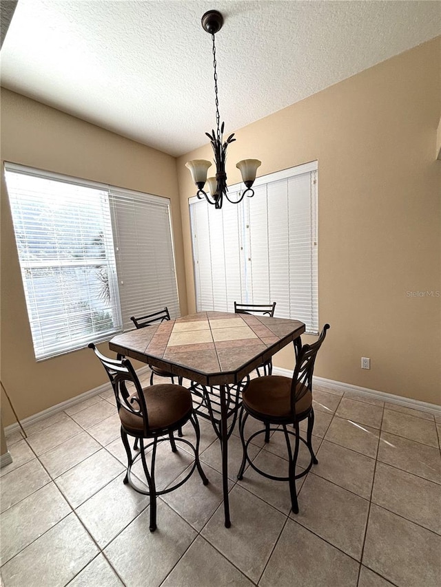 dining space featuring tile patterned flooring, a textured ceiling, and an inviting chandelier