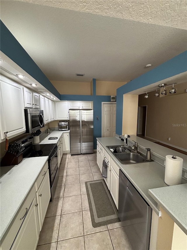 kitchen with white cabinetry, sink, stainless steel appliances, a textured ceiling, and light tile patterned floors