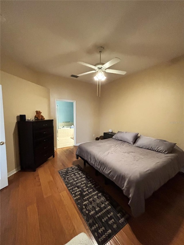 bedroom featuring hardwood / wood-style floors, ceiling fan, and ensuite bath