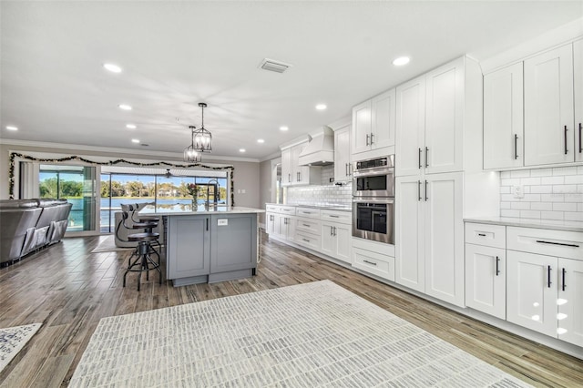 kitchen featuring premium range hood, a breakfast bar, white cabinets, and a center island