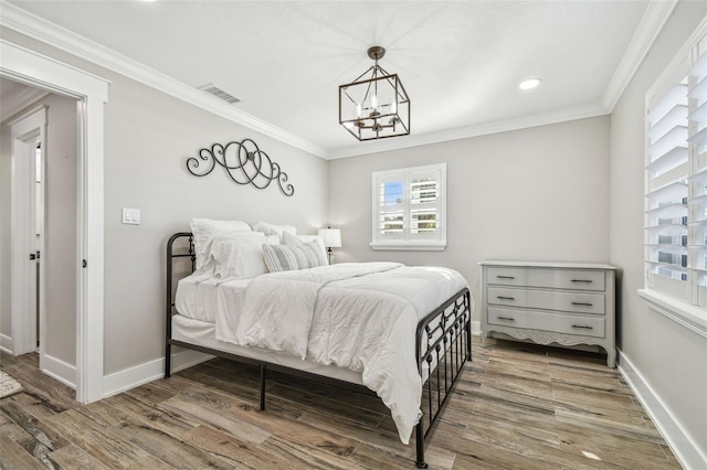 bedroom with hardwood / wood-style flooring, crown molding, and a chandelier