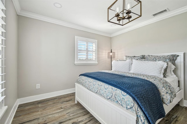 bedroom featuring dark hardwood / wood-style floors, crown molding, and a notable chandelier