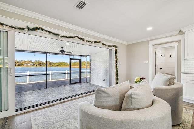 living room with hardwood / wood-style flooring, ceiling fan, a water view, and crown molding