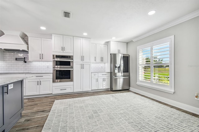 kitchen with white cabinets, stainless steel appliances, premium range hood, and crown molding