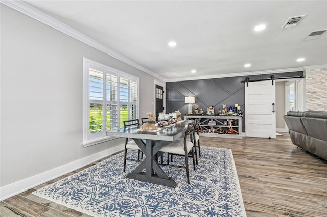 dining area with hardwood / wood-style floors, a barn door, and ornamental molding