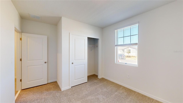 unfurnished bedroom featuring light carpet and a closet