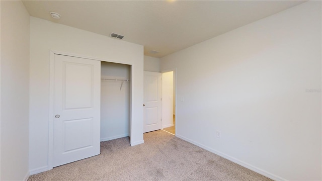 unfurnished bedroom featuring a closet and light colored carpet