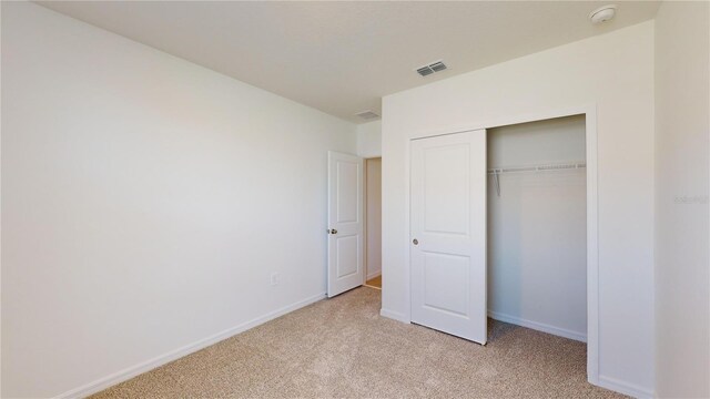 unfurnished bedroom featuring light carpet and a closet