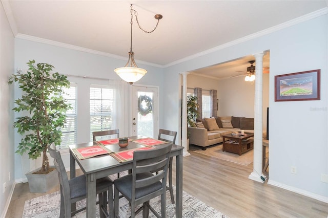 dining area with light wood-type flooring, ornate columns, a healthy amount of sunlight, and crown molding