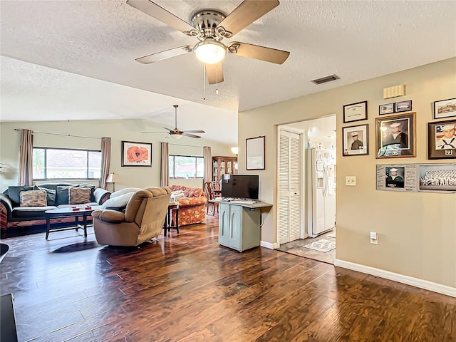 living room featuring a textured ceiling, dark wood-type flooring, plenty of natural light, and lofted ceiling