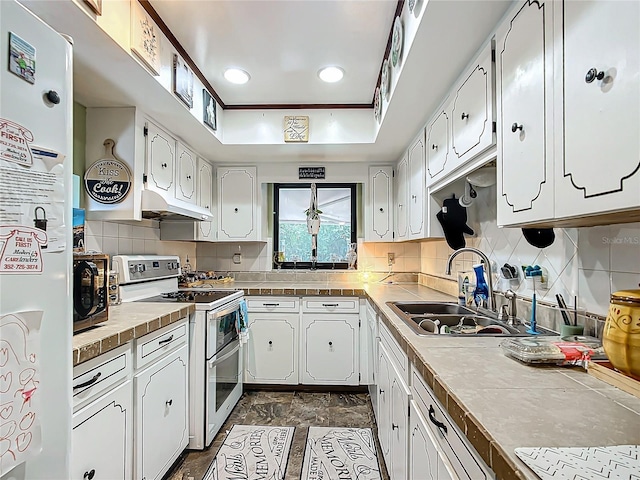 kitchen with tasteful backsplash, white appliances, sink, white cabinets, and tile counters