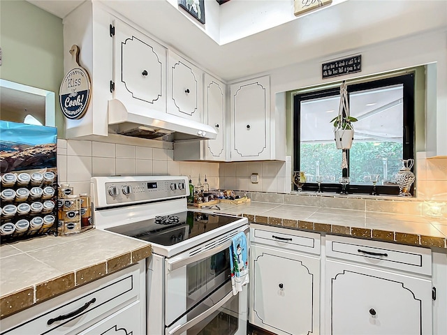 kitchen featuring white cabinets, backsplash, tile countertops, and electric stove