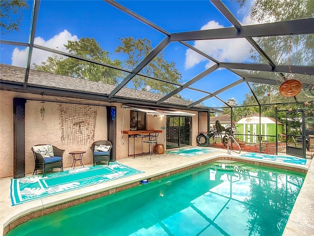 view of swimming pool with a storage unit, a lanai, a patio, and a hot tub