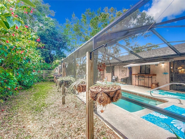 view of swimming pool with a bar, glass enclosure, and a patio area