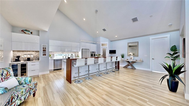 10101 Eagle Preserve Dr, Englewood, FL 34224 - kitchen with modern cabinets, appliances with stainless steel finishes, a kitchen bar, high vaulted ceiling, and a kitchen island