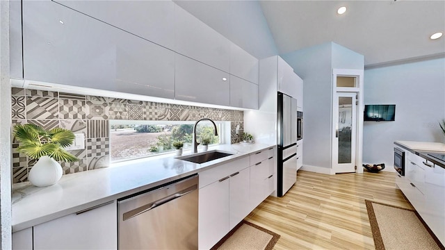 kitchen featuring decorative backsplash, white cabinets, light countertops, stainless steel dishwasher, and a sink