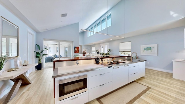 kitchen featuring visible vents, modern cabinets, built in microwave, light wood-type flooring, and white cabinetry