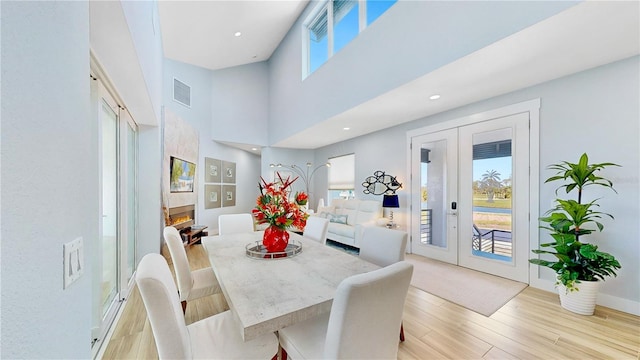 dining room featuring light wood-type flooring, plenty of natural light, visible vents, and french doors