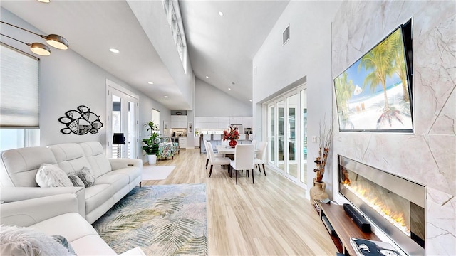 living room with light wood-style floors, plenty of natural light, visible vents, and a high end fireplace