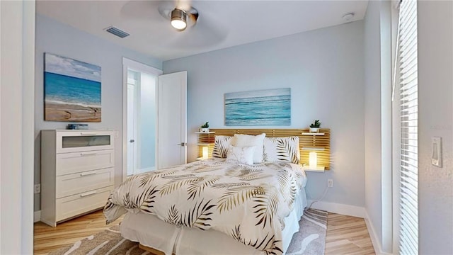 bedroom with light wood finished floors, baseboards, visible vents, and a ceiling fan