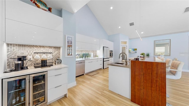 10101 Eagle Preserve Dr, Englewood, FL 34224 - kitchen with modern cabinets, stainless steel appliances, wine cooler, white cabinetry, and tasteful backsplash