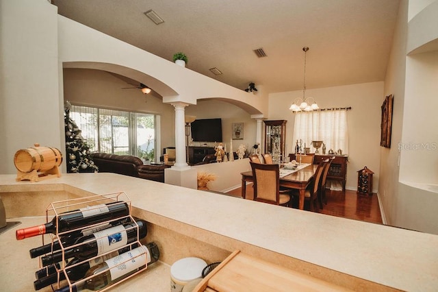 dining room with decorative columns, wood-type flooring, and ceiling fan with notable chandelier