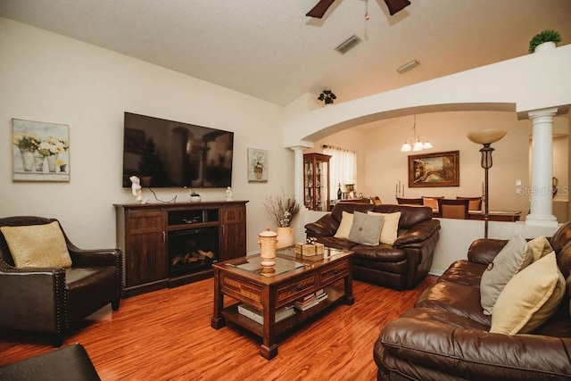 living room with ceiling fan with notable chandelier, hardwood / wood-style flooring, and lofted ceiling