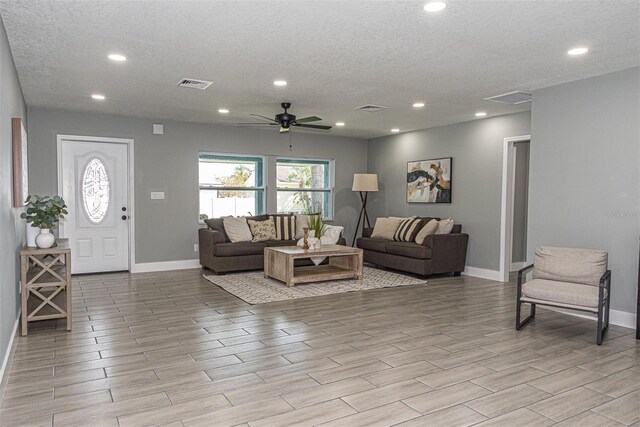 living room featuring a textured ceiling, light hardwood / wood-style flooring, and ceiling fan