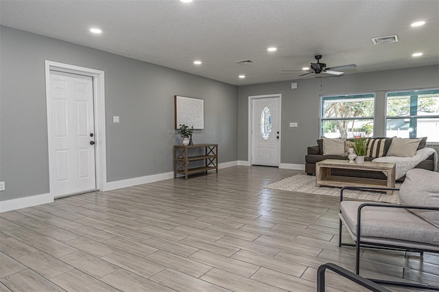 foyer entrance with ceiling fan, a textured ceiling, and light hardwood / wood-style flooring