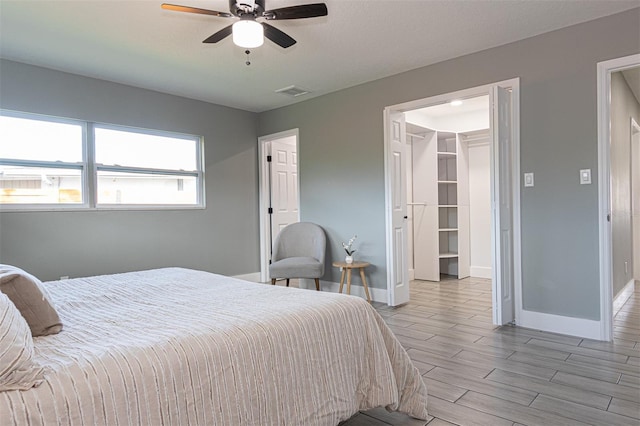 bedroom with ceiling fan, a spacious closet, and light hardwood / wood-style flooring