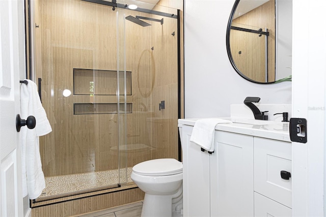 bathroom with a shower with door, vanity, and toilet