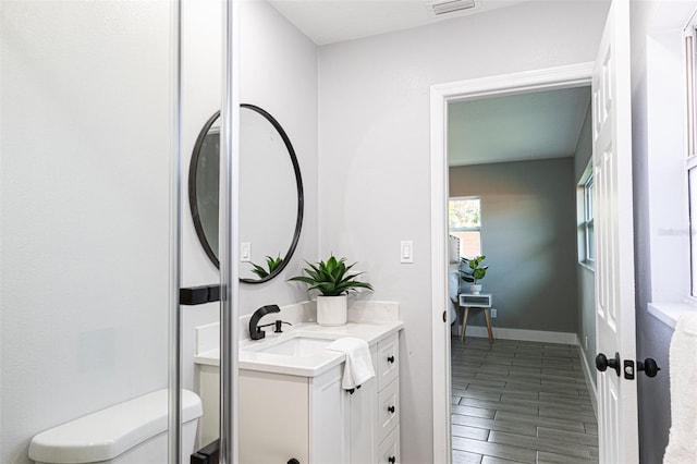 bathroom with hardwood / wood-style floors, vanity, and toilet