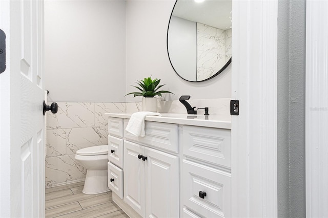 bathroom featuring hardwood / wood-style flooring, vanity, toilet, and tile walls