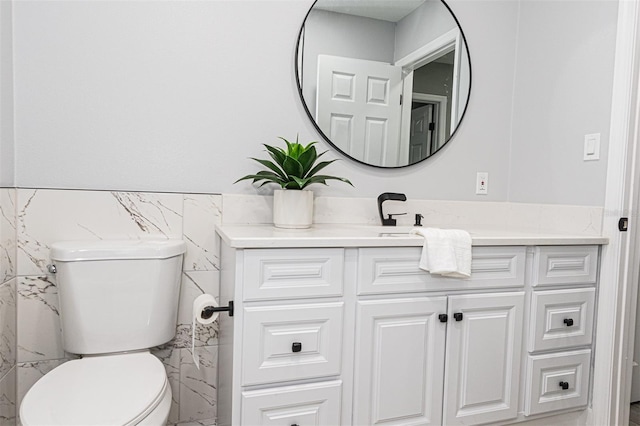 bathroom with vanity, tile walls, and toilet