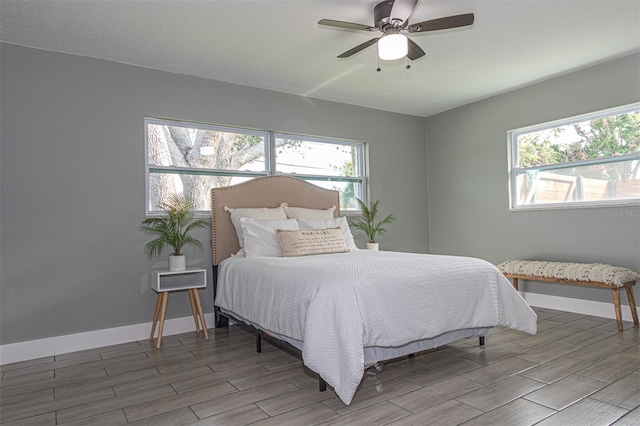 bedroom with multiple windows, ceiling fan, and hardwood / wood-style flooring