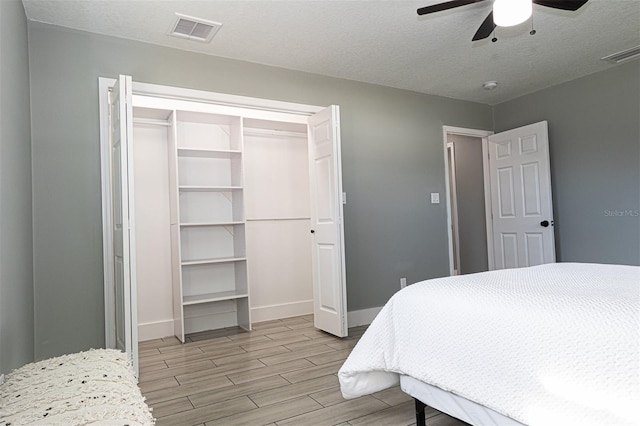 bedroom featuring ceiling fan, light wood-type flooring, a textured ceiling, and a closet