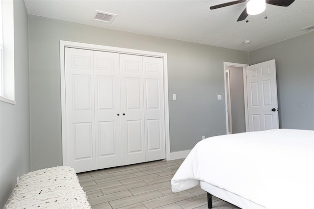 bedroom featuring a textured ceiling, light wood-type flooring, a closet, and ceiling fan