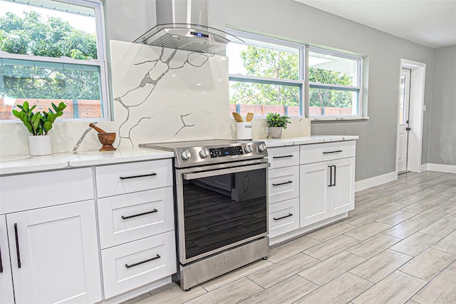 kitchen featuring white cabinetry, island exhaust hood, stainless steel electric range oven, and light stone countertops