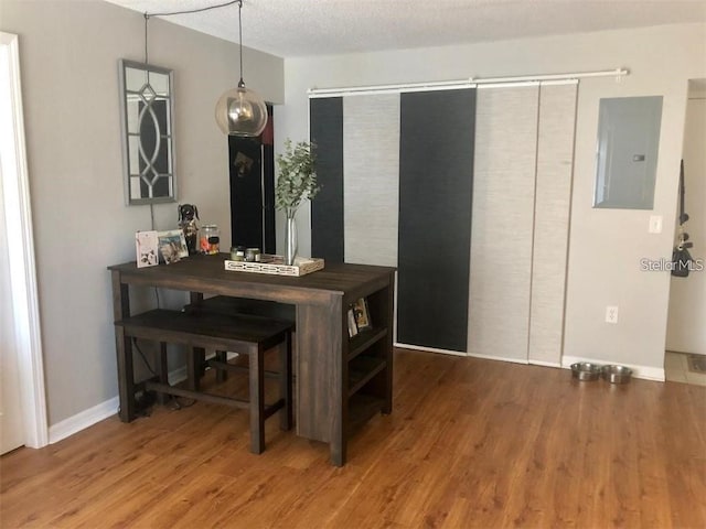 dining space with wood-type flooring, a textured ceiling, and electric panel