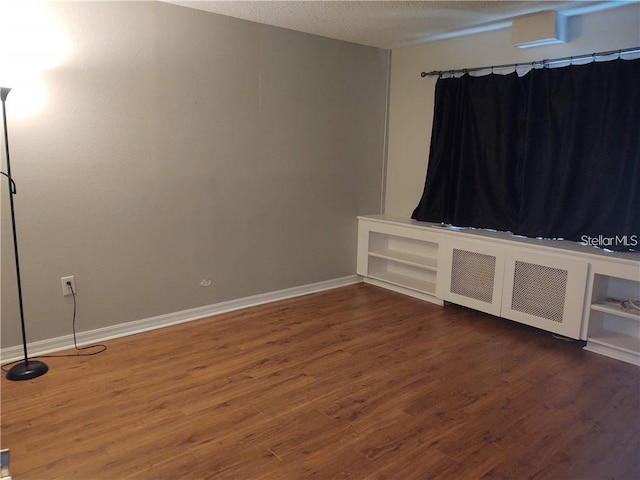 unfurnished room featuring radiator heating unit, a textured ceiling, and dark hardwood / wood-style floors