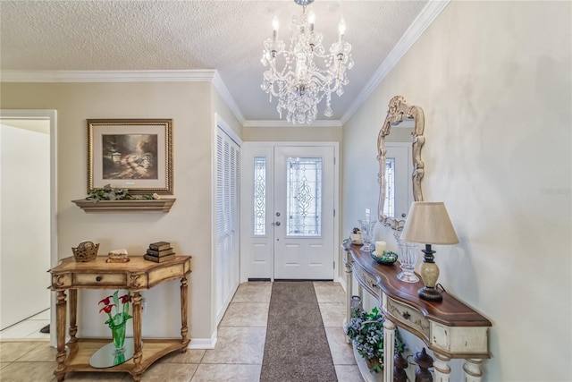 tiled entryway featuring a textured ceiling, ornamental molding, and a notable chandelier