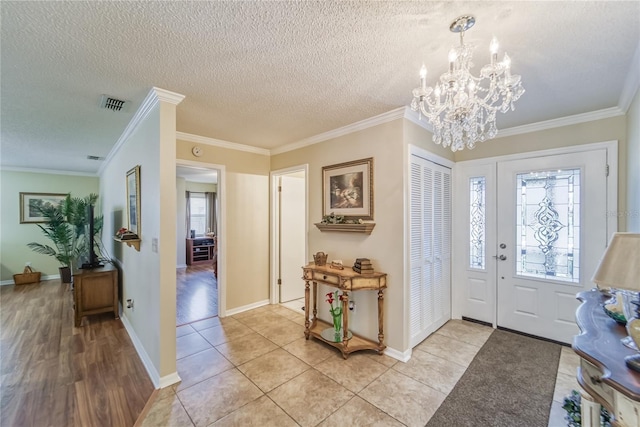 entrance foyer featuring a chandelier, a textured ceiling, light hardwood / wood-style flooring, and ornamental molding